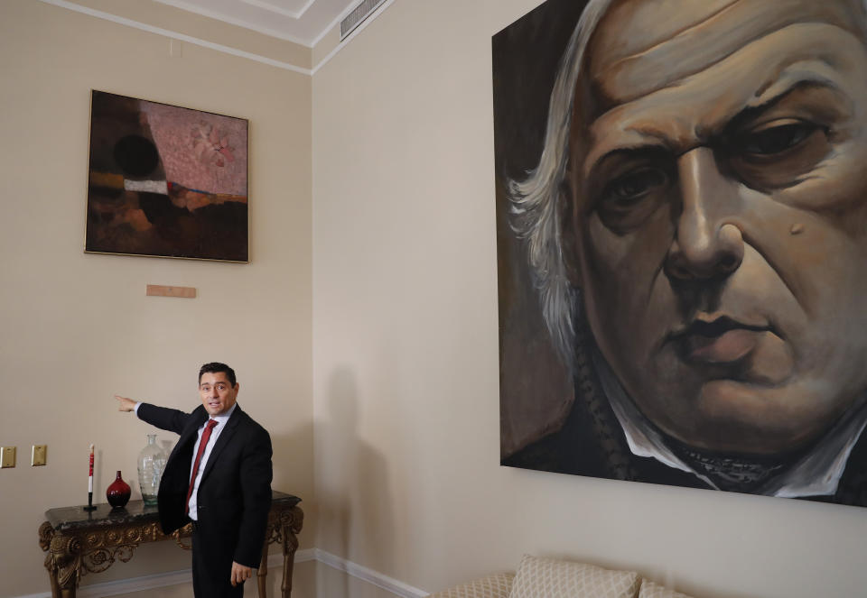 In this Sept. 17, 2019, photo, Carlos Vecchio, an exiled politician who the U.S. recognizes as Venezuela’s ambassador, points to a blank section of a wall where artwork once hung inside the Ambassador's residence in Washington. U.S. officials are investigating the possible looting from Venezuela of valuable European and Latin American artwork they believe is being quietly plundered by government insiders as Nicolas Maduro struggles to keep a grip on power. “This is just the tip of the iceberg,” Vecchio said. “If this is what they’ve managed to do with some artwork at a single diplomatic mission, you can imagine what they’ve done inside Venezuela.” (AP Photo/Pablo Martinez Monsivais)