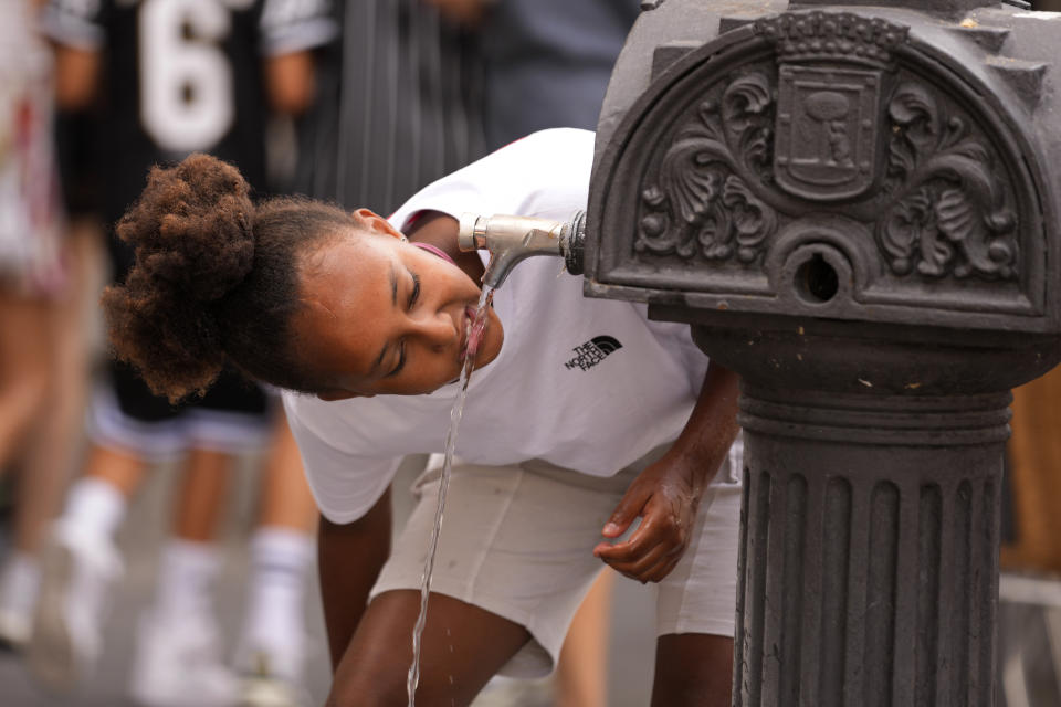 A girl drinks water from a public fountain tap in Madrid, Spain, Tuesday, July 18, 2023. Temperatures are expected to peak today in some Mediterranean countries, with thermometers possibly hitting about 46 Celsius (114.8) in some parts of Spain (AP Photo/Paul White)