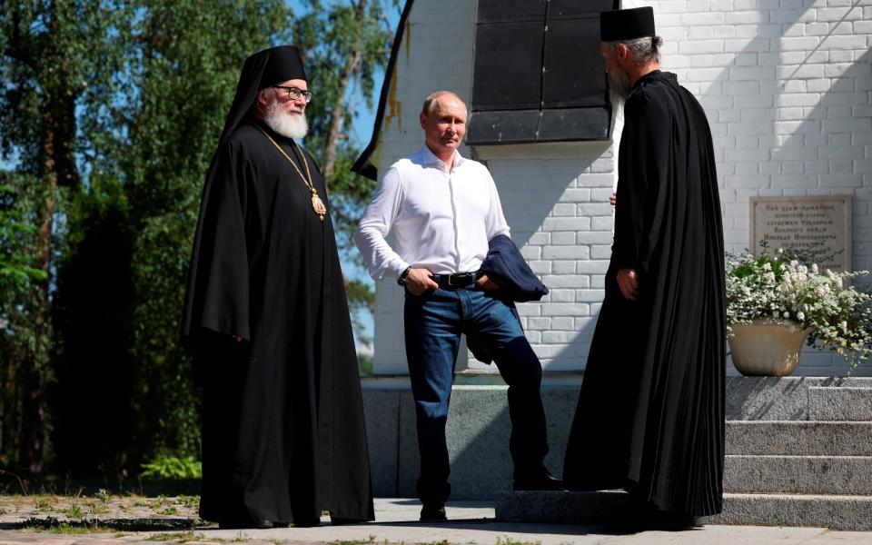 Vladimir Putin listens to clergymen as he visits the Valaam Monastery in the Republic of Karelia