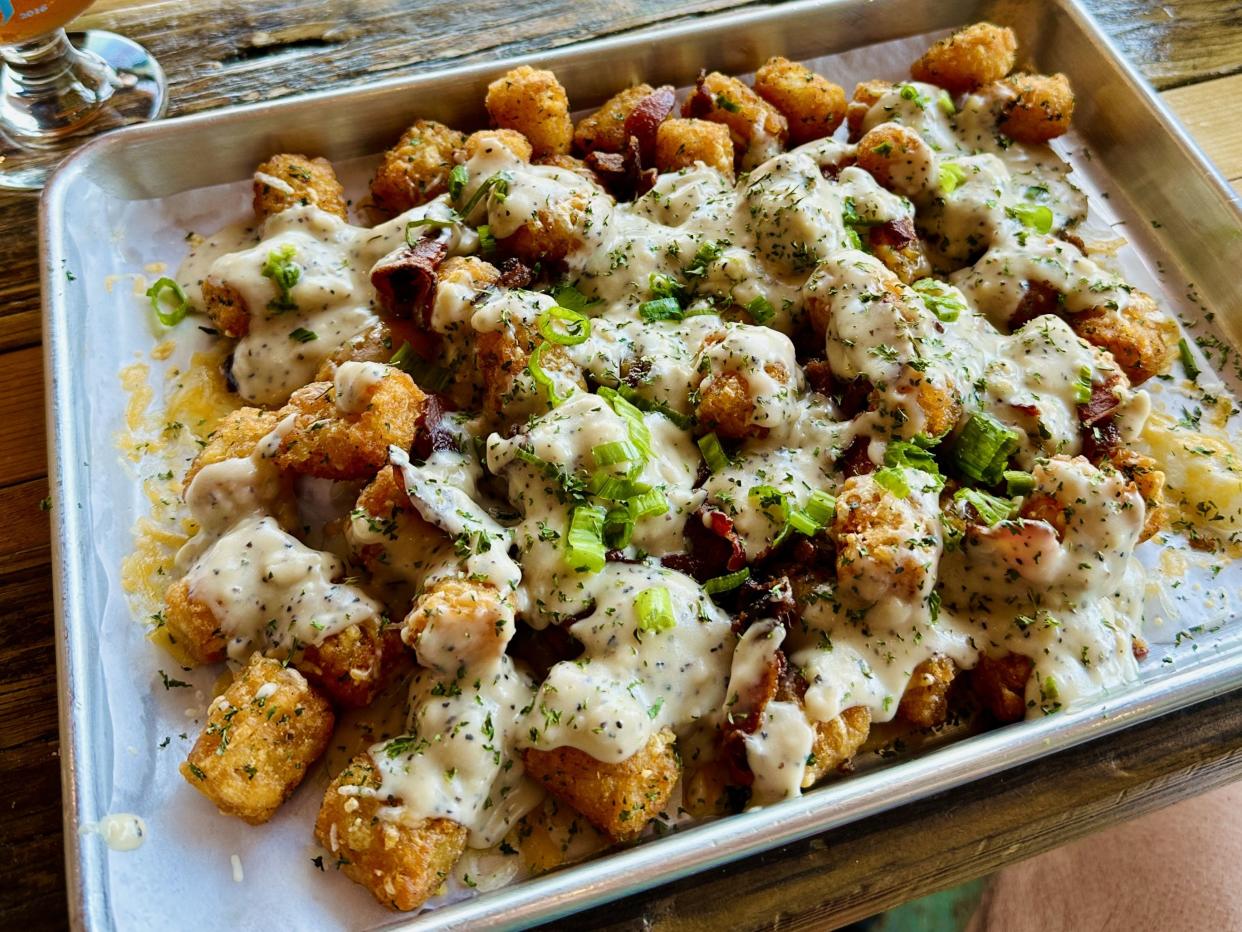 A large tray of fried loaded tater tots made with cheese sauce, savory chicken gravy, bacon, and other toppings.