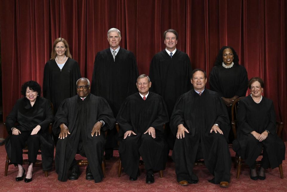 A group of nine people in black robes, seated in two rows.