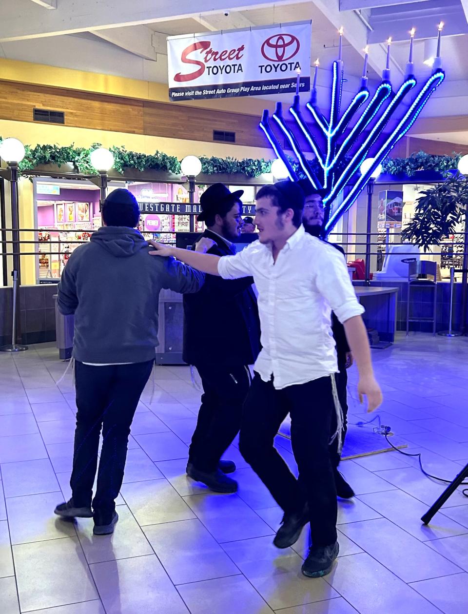 Members of the Roving Rabbis dance to the music performed at the Hanukkah Menorah presented Tuesday evening at Westgate Mall.