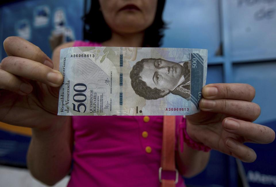 Un cliente muestra un billlete nuevo de 500 bolívares fuera de un banco en Caracas, Venezuela, el lunes 16 de enero de 2017. (AP Foto/Fernando Llano)