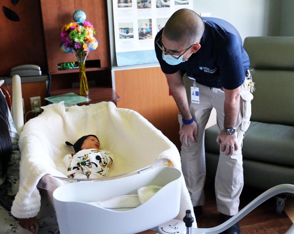 Wentworth-Douglass Hospital security guard Andy Clark bends over to take a look at Tiago Gonzalez in the birthing unit at the Dover hospital Friday, Sept. 16, 2022. Clark helped deliver the baby in a car in the parking lot.