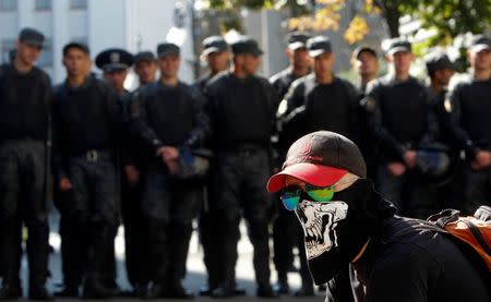 A protester sits in front of a line of riot police during a rally against the laws to provide separatist-held regions with a special status near the Ukrainian parliament in Kiev, September 17, 2014. REUTERS/Valentyn Ogirenko