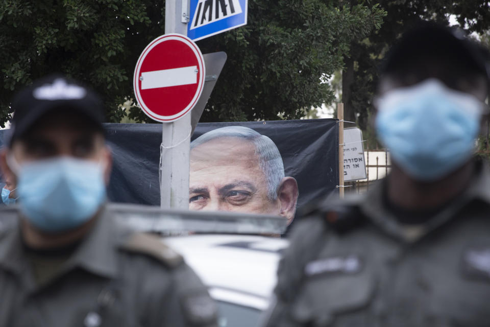 Police stand guard as Israeli anti-government protesters chant slogans outside of the official residence of Prime Minister Benjamin Netanyahu on the day his corruption trial was originally scheduled before it was postponed, in Jerusalem, Wednesday, Jan. 13, 2021. (AP Photo/Maya Alleruzzo)