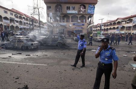 Policemen walk towards burnt vehicles at the scene of a blast at a business district in Abuja June 25, 2014. REUTERS/Afolabi Sotunde