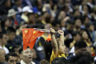 A child holds up two Chinese national flags as she watches a preseason NBA basketball game between the Brooklyn Nets and Los Angeles Lakers at the Mercedes Benz Arena in Shanghai, China, Thursday, Oct. 10, 2019. (AP Photo)