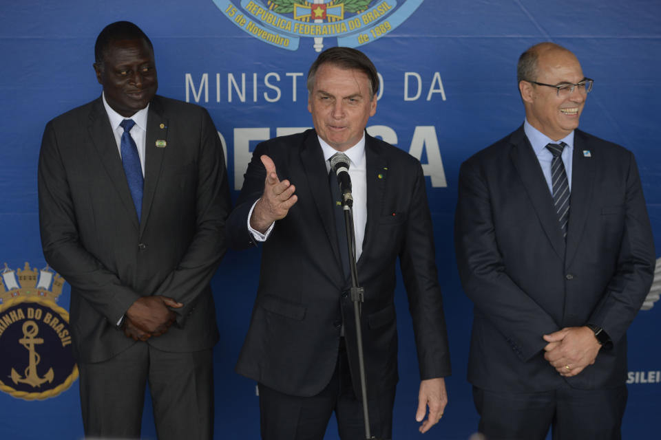 In this photo released by Agencia Brasil, Brazil's President Jair Bolsonaro, center, Rio de Janeiro's Governor Governor Wilson Witzel, right, and Former Army Sub-Lieutenant and Federal Deputy Helio Fernando Barbosa Lopes, attend a military ceremony celebrating "Victory Day" marking the participation of Brazil in World War II, in Rio de Janeiro, Brazil, Wednesday, May 8, 2019. Bolsonaro said Rio de Janeiro will host the country's Formula One race in 2020, once the new autodrome is ready. (Tomaz Silva/Agencia Brasil via AP)