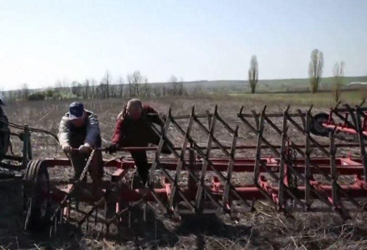 Ukrainian farmers work a field in the country's south amid Russia's ongoing military invasion, in June 2022. / Credit: CBS News