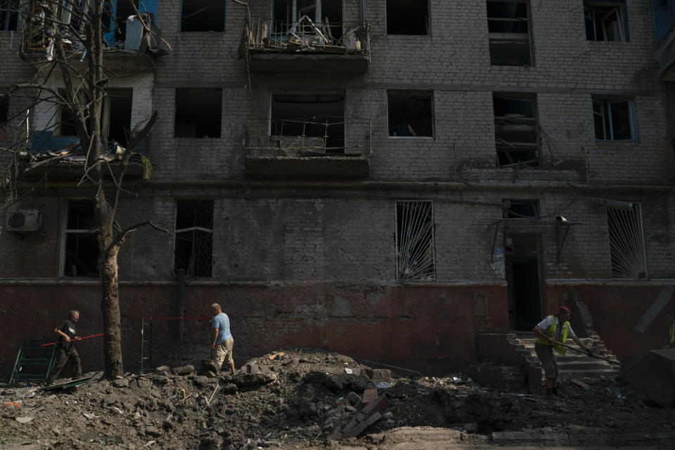 People work to clean up debris in front of a residential building that was damaged after a Russian attack in Kramatorsk, Ukraine, Wednesday, Aug. 31, 2022. (AP Photo/Leo Correa)