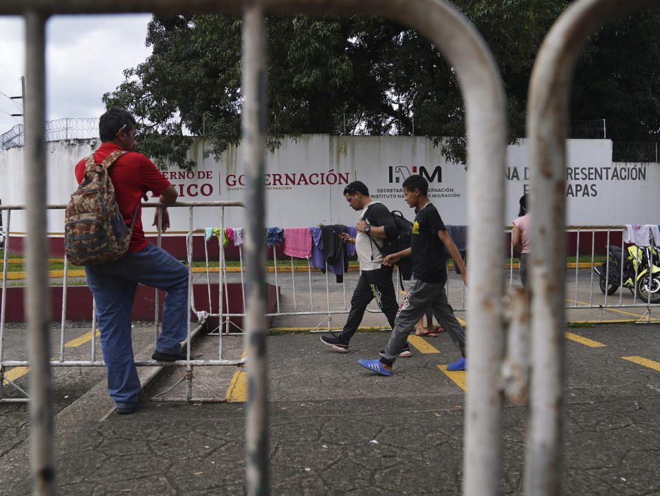 Migrants walk outside the National Immigration Institute in Tapachula, Chiapas state, Mexico, Tuesday, Oct. 3, 2022. When migrants arrive to the main crossing point into southern Mexico they soon learn the only way to cut through the red tape and speed up what can be a months-long process is to pay someone. (AP Photo/Marco Ugarte)