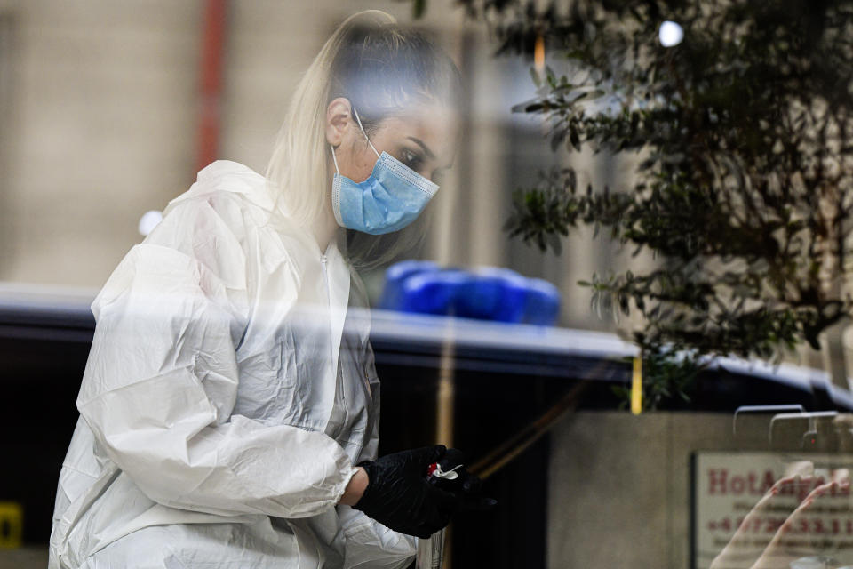 A forensic worker collects body parts and evidence from a hotel downtown Bucharest, Romania, Friday, June 19, 2020. Gholamreza Mansouri, a former judge from Iran sought by his country to face corruption charges has died after falling from a high floor inside a hotel. Romanian police said only that a man had fallen from a high floor at a hotel in Bucharest, the Romanian capital, and was found dead. (AP Photo/Andreea Alexandru)