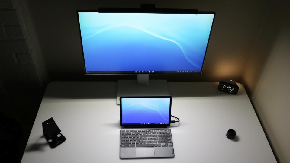 An overhead shot of a desk setup lit by a monitor light bar at night