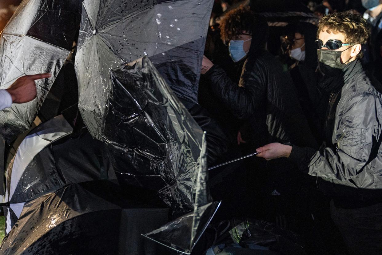 Demonstrators use umbrellas as shields in a protest over Sunday's fatal shooting of Daunte Wright during a traffic stop outside the Brooklyn Center Police Department on Wednesday, April 14, 2021, in Brooklyn Center, Minn.