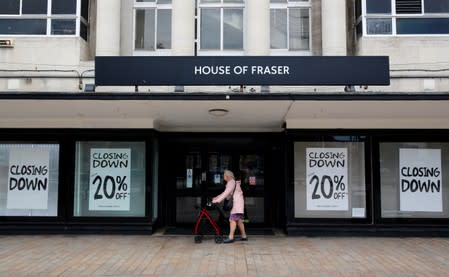 A woman walks past a House of Fraser store that has closing down posters in the windows, in Hull