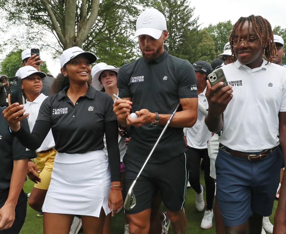 Stephen Curry autographs a golf ball as he walks with Underrated Golf tour players on the 18th hole on the South Course at Firestone Country Club in Akron.