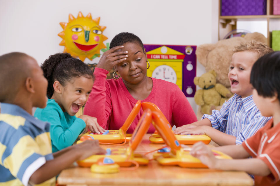 A teacher looking stressed with children at a desk