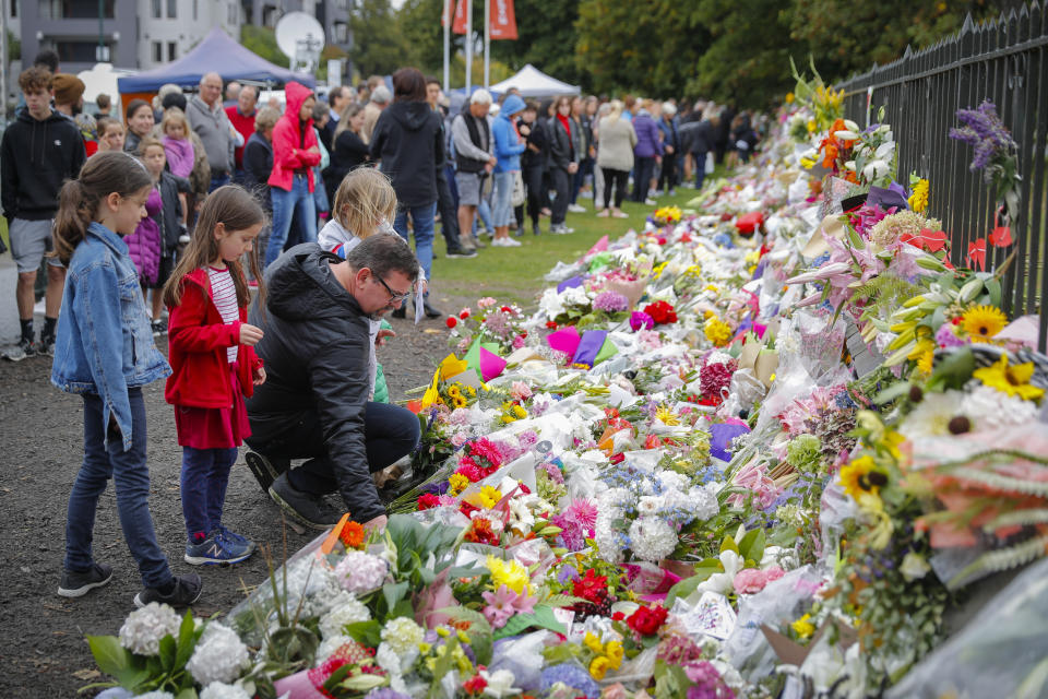 CORRECTS DATE- Mourners lay flowers on a wall at the Botanical Gardens in Christchurch, New Zealand, Sunday, March 17, 2019. New Zealand's stricken residents reached out to Muslims in their neighborhoods and around the country on Saturday, in a fierce determination to show kindness to a community in pain as a 28-year-old white supremacist stood silently before a judge, accused in mass shootings at two mosques that left dozens of people dead. (AP Photo/Vincent Thian)