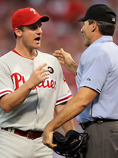 Phillies pitcher Roy Oswalt talks with home-plate umpire Angel Hernandez after a squirrel ran across home plate during a pitch