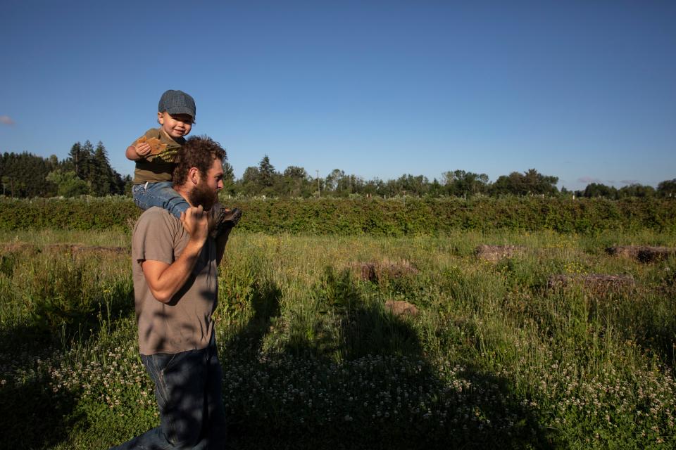 Graham Fordyce carries his son, Damien, nearly 2, as they prepare to irrigate the fields at Fordyce Farm.