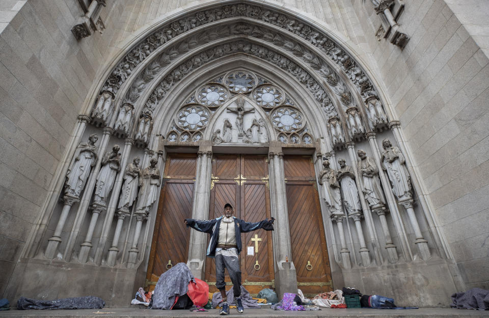 A homeless man gestures to the camera after waking up from sleeping overnight outside the Cathedral, amid the spread of the new coronavirus in Sao Paulo, Brazil, Thursday, May 7, 2020. According to the Sao Paulo municipal office of social assistance and welfare, at least 22 homeless people have died of COVID-19 in the past few weeks. (AP Photo/Andre Penner)