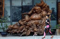 A woman walks past a laughing Buddha sculpture near the venue where the G20 Finance Ministers and Central Bank Governors Meeting will be held over the weekend in Chengdu in Southwestern China's Sichuan province, July 22, 2016. REUTERS/Ng Han Guan/Pool