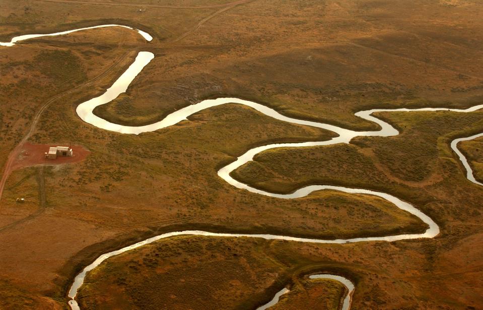 A river of water snakes through the brown landscape of the Powder River Basin in Wyoming
