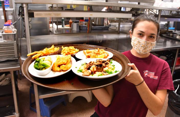 Alesha York takes an order from the kitchen at Dixie Crossroads in Titusville, Florida.