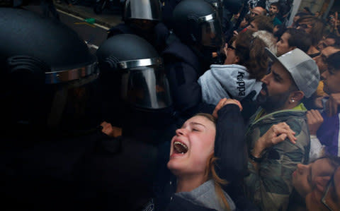A woman grimaces as Spanish National Police pushe away pro-referendum supporters - Credit: AP Photo/Emilio Morenatti