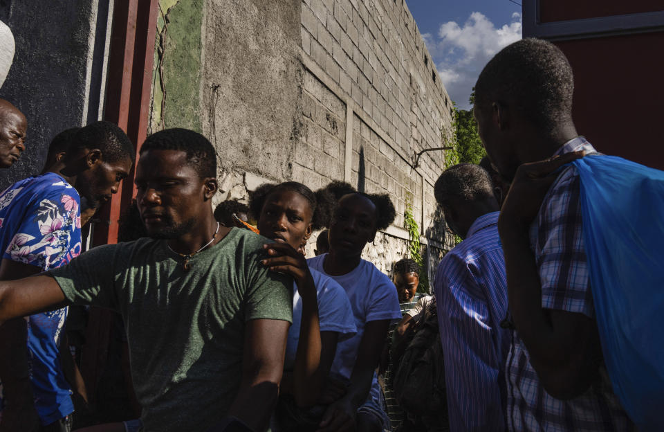 Neighbors pass in and out of a passageway as others erect a metal gate as protection against gangs, in the Petion-Ville neighborhood of Port-au-Prince, Haiti, Saturday, April 20, 2024. (AP Photo/Ramon Espinosa)