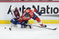 Colorado Avalanche defenseman Bowen Byram (4) and Florida Panthers center Eetu Luostarinen (27) battle for the puck during the second period of an NHL hockey game, Saturday, Feb. 10, 2024, in Sunrise, Fla. (AP Photo/Wilfredo Lee)