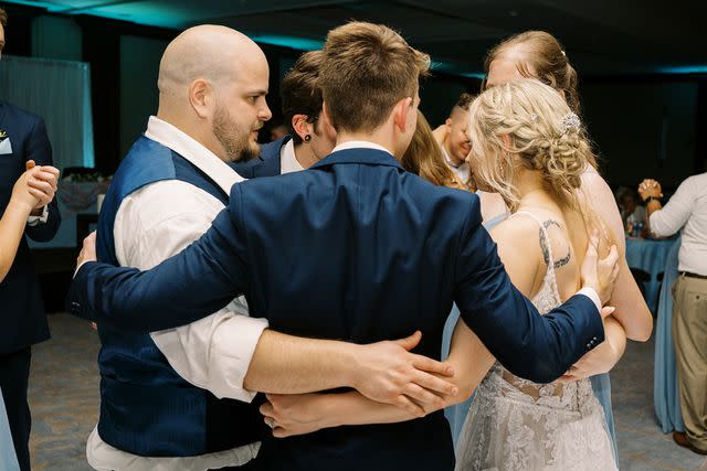 <p>Derrick Parsons</p> Alex and Sarah hugging guests at the wedding