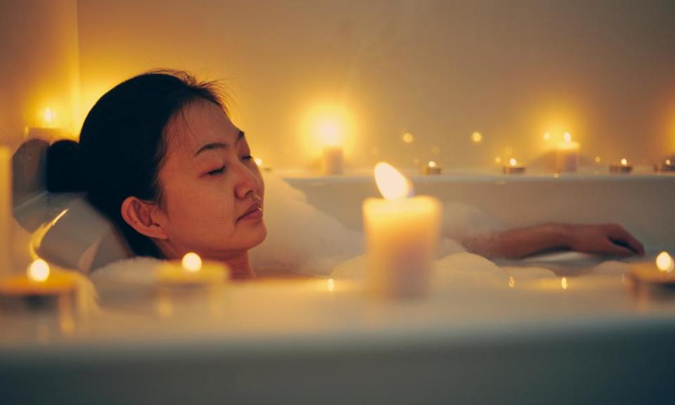 A woman relaxes in a candlelit bath