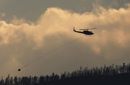 A helicopter flies over a wildfire south west of the town of Cache Creek, British Columbia, Canada July 18, 2017. Picture taken July 18, 2017. REUTERS/Ben Nelms