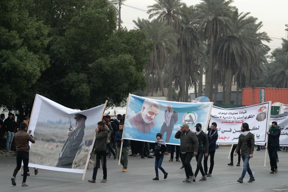 Supporters and members of the Popular Mobilization Forces hold posters of a powerful Iranian general and a top Iraqi militia leader in Baghdad, Iraq, Saturday, Jan. 1, 2022. Hundreds rally in Baghdad on Soleimani assassination anniversary, chanting anti-American slogans, hundreds of people rallied in in the Iraqi capital on the first day of the year Saturday to mark the anniversary of the killing of a powerful Iranian general and a top Iraqi militia leader in a U.S. drone strike. (AP Photo/Khalid Mohammed)