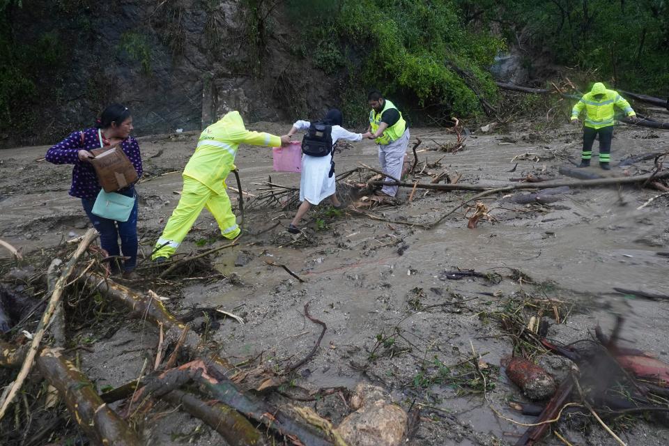 People get help crossing a highway blocked by a landslide triggered by Hurricane Otis near Acapulco, Mexico, Wednesday, Oct. 25, 2023 (AP)