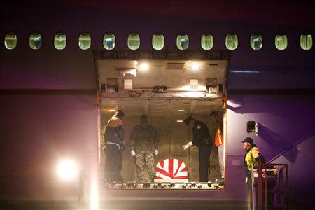 The casket of U.S. Army Sgt. Joseph Gantt is prepared to be lowered from the plane before dawn on the tarmac at Los Angeles International Airport in Los Angeles, California December 20, 2013. REUTERS/Andrew Renneisen/Los Angeles Times/Pool