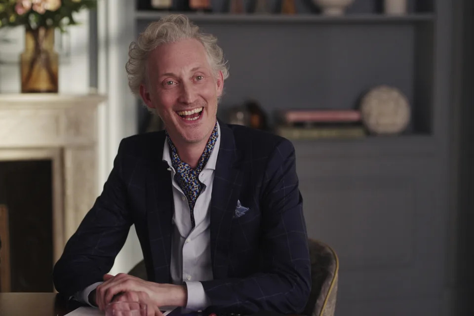 Bruno Gouery in a suit while smiling in "Emily in Paris"