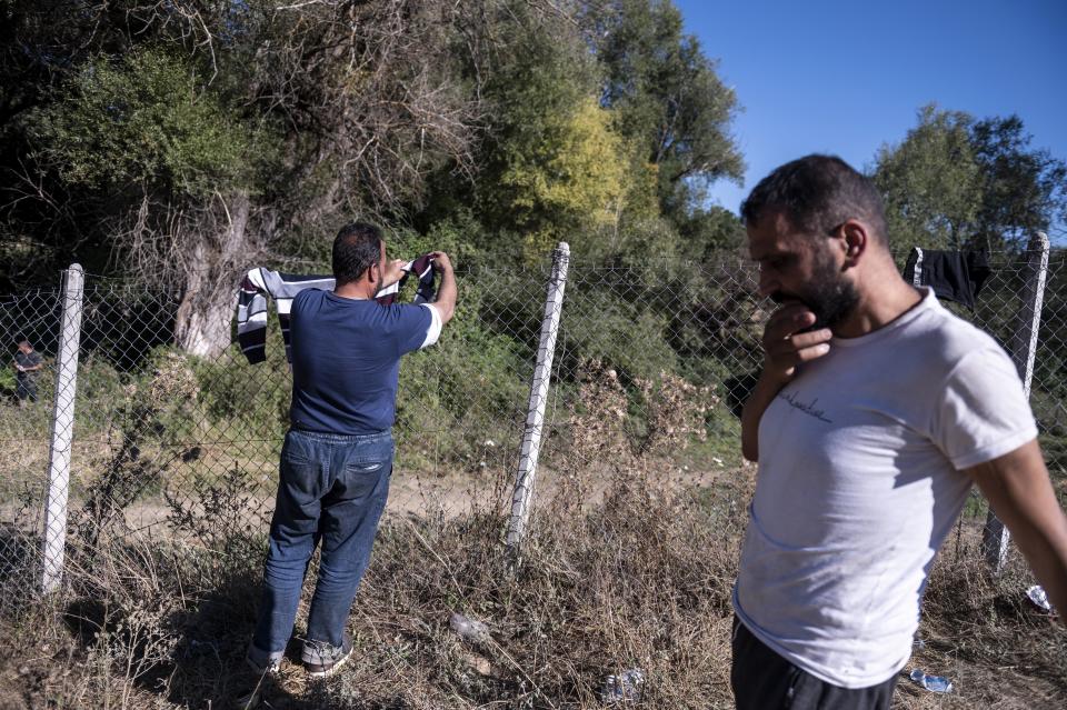 A Syrian migrant dries his washed clothes near Ieropigi village, northern Greece, at the Greek - Albanian border, on Saturday, Sept. 25, 2021. A relatively smooth section of Greece's rugged border with Albania is turning into a major thoroughfare north for migrants in Greece seeking a better life in Europe's prosperous heartland. (AP Photo/Giannis Papanikos)