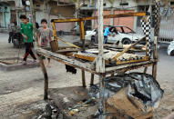 Civilians inspect damage in the aftermath of a Monday car bomb attack in a crowded commercial street in Baghdad's eastern neighborhood of Sadr City, Iraq, Tuesday, April 22, 2014. Suicide bombings and other attacks across Iraq killed and wounded dozens on Monday, officials said, the latest in an uptick in violence as the country counts down to crucial parliamentary elections later this month. (AP Photo/Karim Kadim)