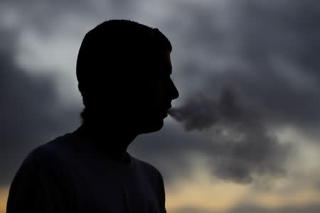 A young man smokes a Suorin Drop electronic cigarette in this picture illustration taken September 14, 2018. REUTERS/Mike Blake/Illustration