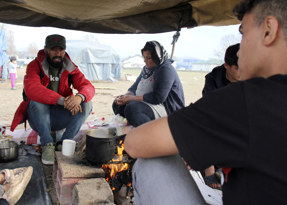Ibrahim Rasool, Afghan refugee, formerly a FIFA-licensed futsal referee, left, sits with other migrants around a fire at a makeshift camp housing migrants, in Velika Kladusa, Bosnia, Saturday, Nov. 13, 2021. Ibrahim Rasool loved his job as a futsal referee because of sportsmanship and fair play. But the 33-year-old man from Afghanistan says there is nothing fair about the way the European Union treats people seeking refuge from violence and war. (AP Photo/Edvin Zulic)