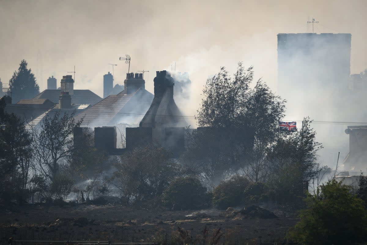 A Union Flag flies amongst the smouldering ruins of houses as fire services tackle a large blaze on July 19, 2022 in Wennington, England.  (Getty Images)