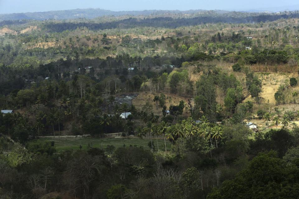 In this Oct. 22, 2018, photo, O'of village is seen from a high point in West Timor, Indonesia. The region is one of the driest parts of Indonesia, making farming difficult. Many villagers thus migrate to neighboring Malaysia in search of work. (AP Photo/Tatan Syuflana)