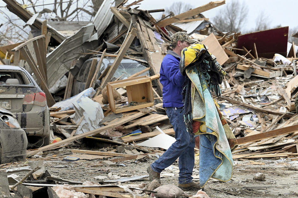 Sullivan resident Joe Reed carries blankets to a car as he and his family salvage what they can, Saturday, April 1, 2023, in Sullvian, Ind., after a tornado moved through the area late the night before. (Joseph C. Garza/The Tribune-Star via AP)