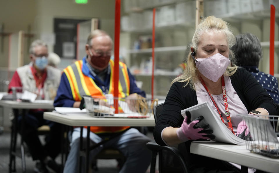 Shawna Weir, right, ballot processing manager for Jefferson County Elections Division, works along with election judges Anthony Tierney, center, and Jim Everson to process early ballots, Tuesday, Oct. 26, 2021, in Golden, Colo. Officials were highlighting the steps taken to ensure that the election is carried out seamlessly. (AP Photo/David Zalubowski)