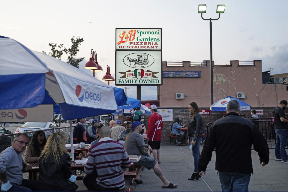 People dine outside at L&B Spumoni Gardens, Sunday, Oct. 4, 2020, in the Brooklyn borough of New York. The popular Brooklyn eatery is located in one of the Zip Codes that have seen a spike in coronavirus cases recently. New York's mayor said Sunday that he has asked the state for permission to close schools and reinstate restrictions on nonessential businesses in several neighborhoods, including that of Spumoni Gardens, because of a resurgence of the virus. (AP Photo/Kathy Willens)