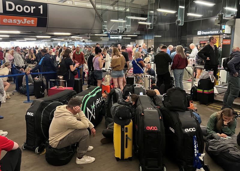 Passengers queue outside Terminal 1 after an overnight power cut led to disruptions and cancellations at Manchester Airport in Manchester