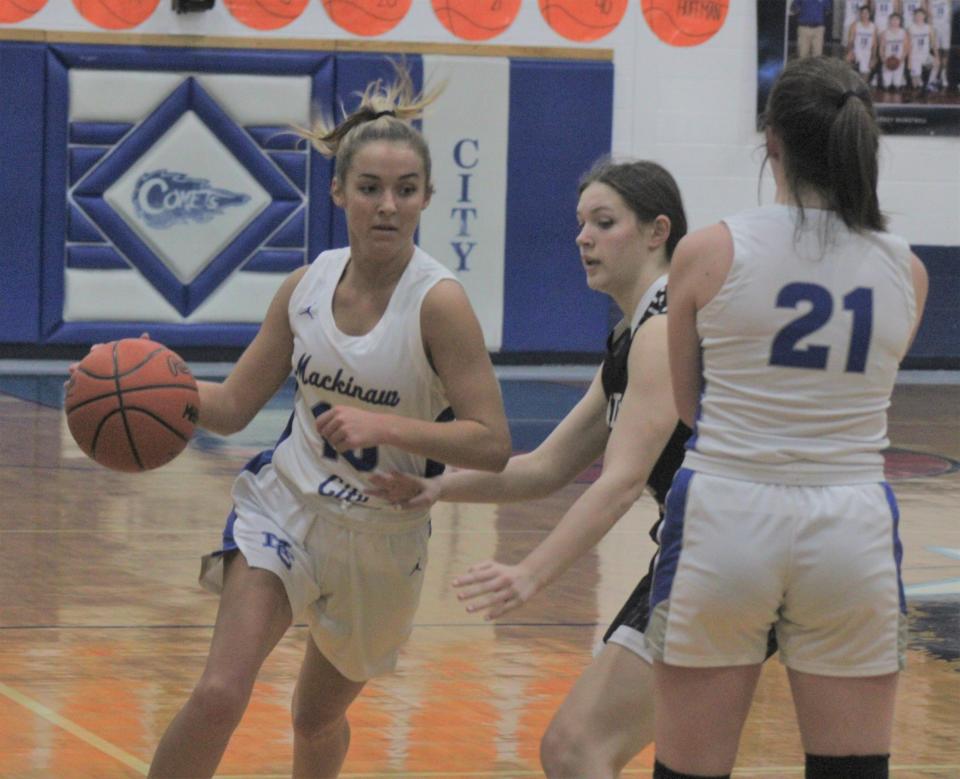 Mackinaw senior guard Marlie Postula (left) goes around a screen set by senior teammate Julia Sullivan (21) during the first half of Friday night's district final clash with Cedarville. Postula finished with a team-high 16 points for the Comets.